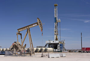 pumpjack and drill rig over an oil well in the permian basin near midland, texas 1200x810