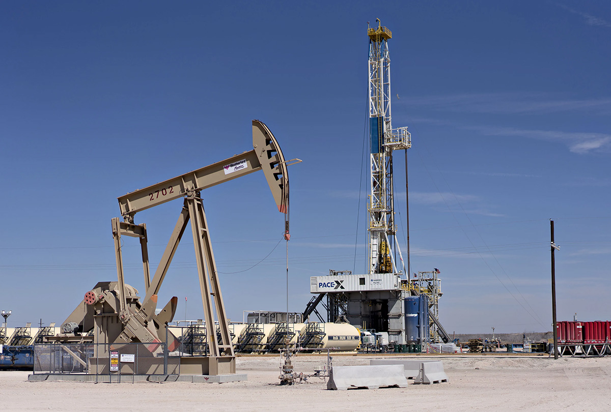 pumpjack and drill rig over an oil well in the permian basin near midland, texas 1200x810